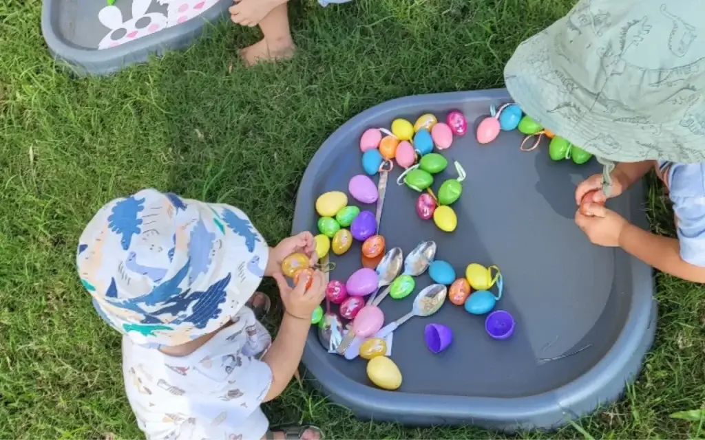Two preschoolers working together to build a block tower, smiling and communicating as they play